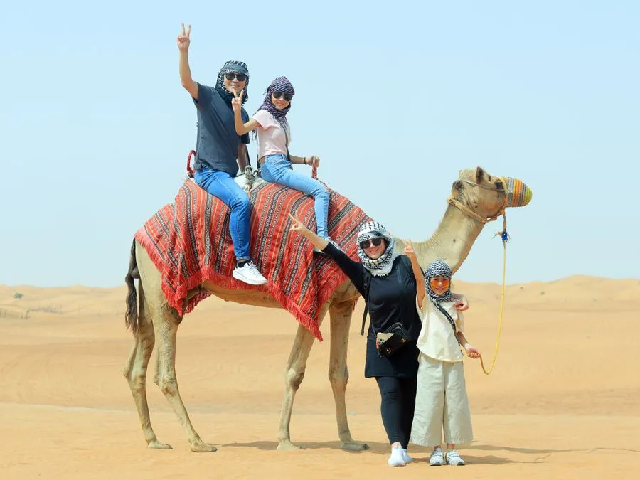 Family group posing with a camel in the desert
