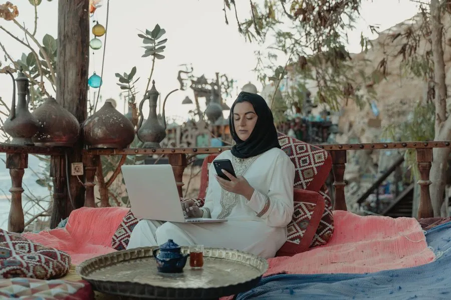 Woman planning a trip on a laptop in a traditional majlis