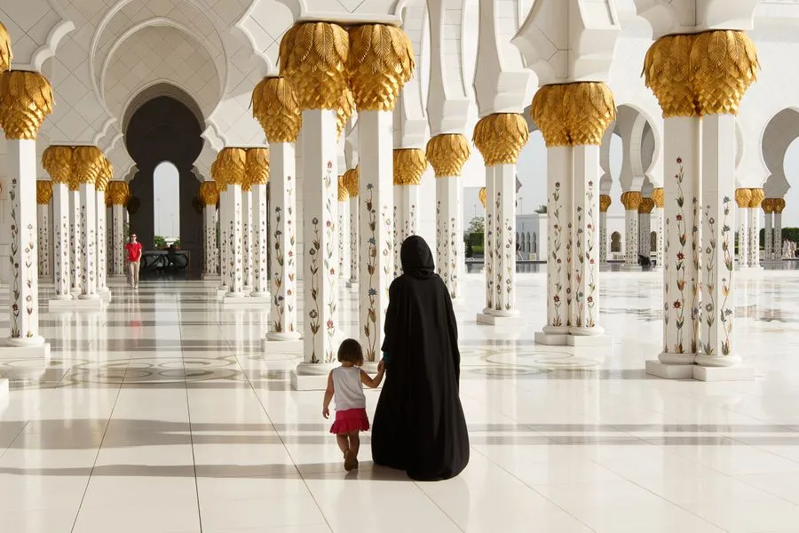 Mother and child walking through the colonnade of Sheikh Zayed Grand Mosque